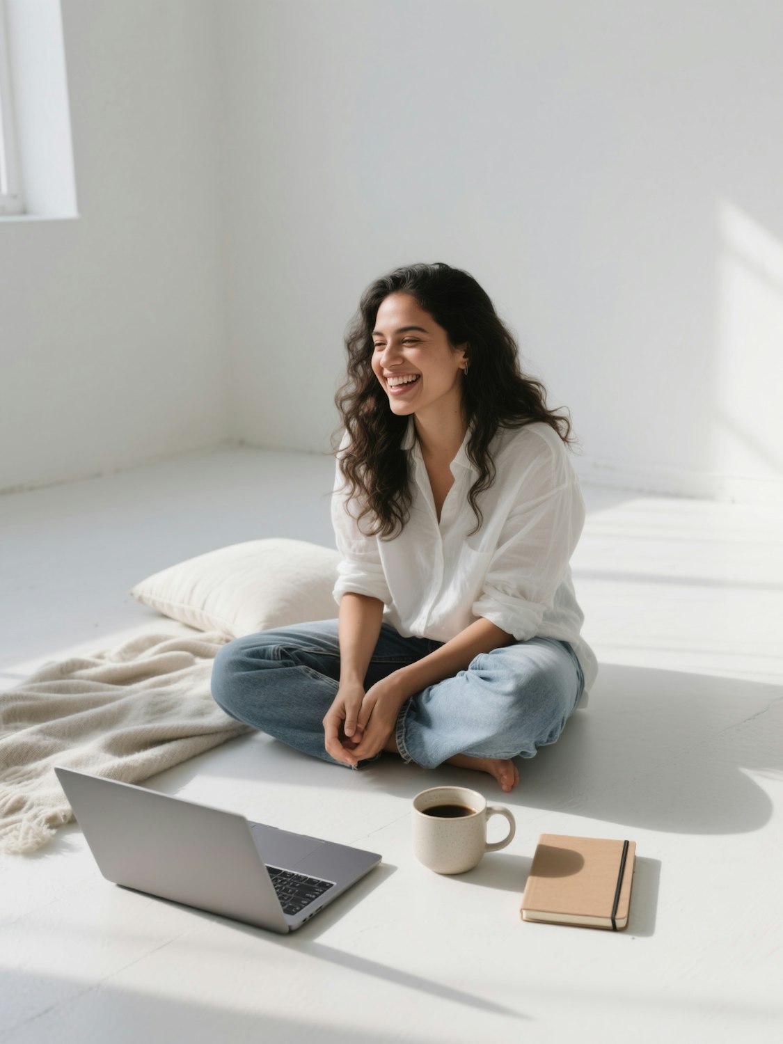 Woman sitting on the floor with a laptop, notebook and coffee
